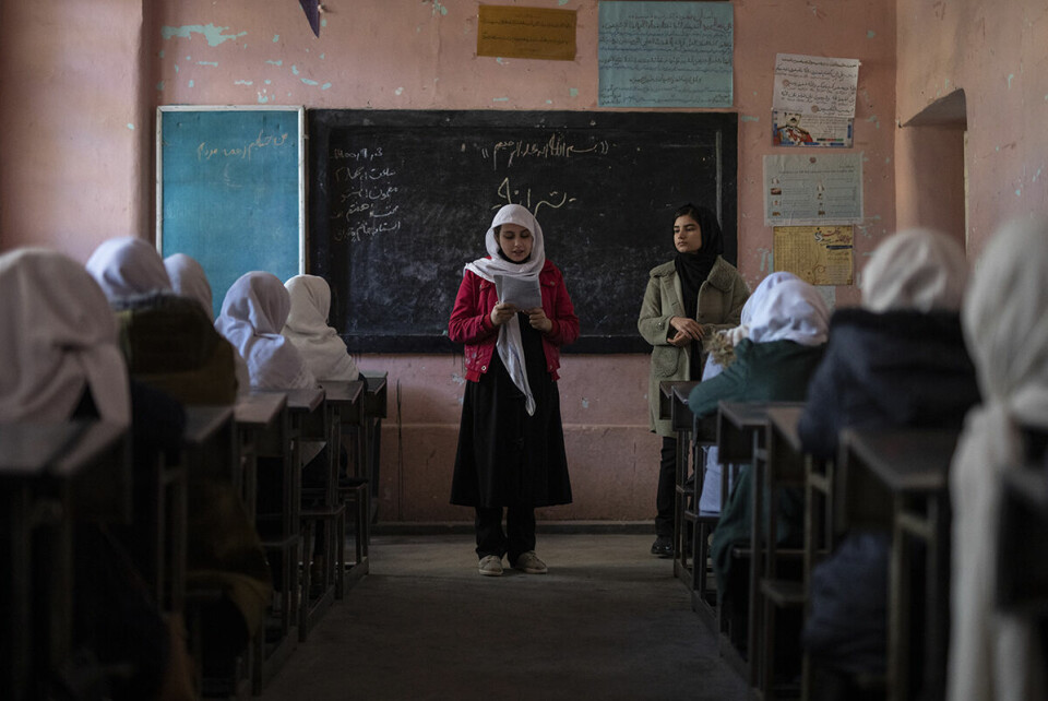 En afghansk jente leser høyt for klassen mens læreren følger med. Undervisningen skjer ved Tajrobawai skole i Herat. Disse jentene er heldige, rundt om ellers i landet får jenter ikke gå på videregående skoler. Foto: Petros Giannakouris / AP / NTB