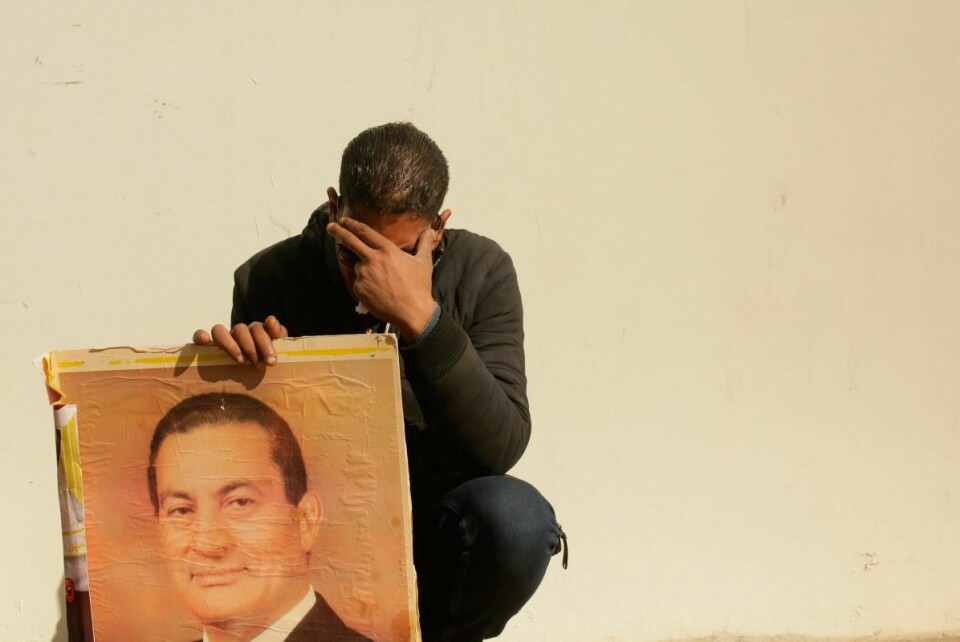 En sørgende mann med et bilde av Egypts styrtede president Hosni Mubarak under begravelsen 26. februar. Foto: Maya Alleruzzo / AP / NTB