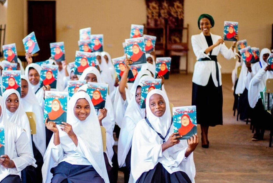 Nancy Sumari viser fram en kopi av sin siste bok, sammen med jenter ved Kizimkazi videregående skole i Zanzibar. Foto: Privat