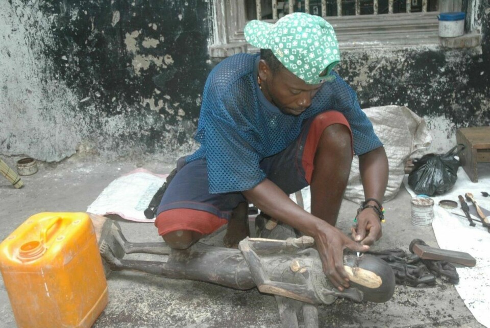 En kunstner lager øyenhuler gjennom å beskjære ansiktet på en treskulptur. Mange av trekunstnerne i Tanzania pleide å livnære seg på å selge kunsten de lager til turister. Nå har reiserestriksjonene som har blitt innført for å begrense spredningen av koronaviruset ført til at de fleste av disse håndverkerne har havnet i en alvorlig økonomisk situasjon. Foto: Zuberi Mussa