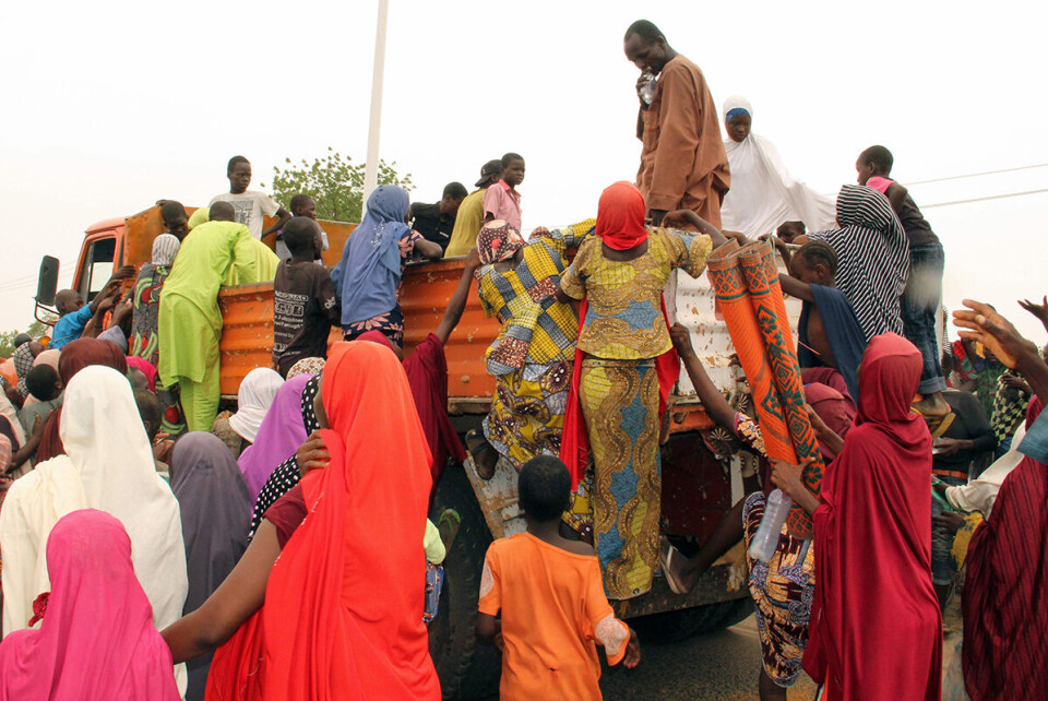 Kvinner og barn fordrevet fra sine hjem av Boko Haram forsøker å komme seg opp på en lastebil som kan frakte dem bort fra leiren der de mangler mat. Foto: AFP /NTB