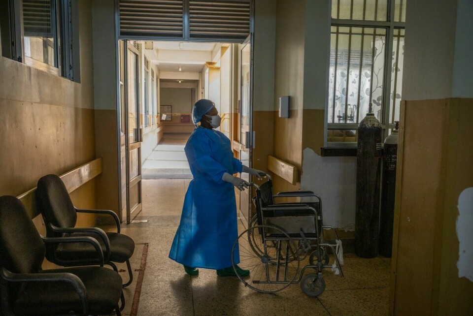 En omsorgsarbeider ved sykehuset i Entebbe har hentet en rullestol for hente en pasient som har blitt utskrevet.