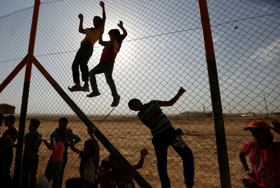 Syriske flyktningbarn har klatret opp på et gjerde i Al Zaatri-flyktningleiren i Jordan for å se på trofeet til kvinnenes U-17 verdensmesterskap i fotball som blir fraktet gjennom leiren.