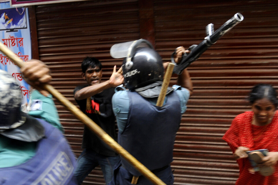 En mann blir angrepet av politiet under en demonstrasjon for bedre arbeidsforhold for tekstilarbeidere i Dhaka. Foto: AFP / NTB scanpix