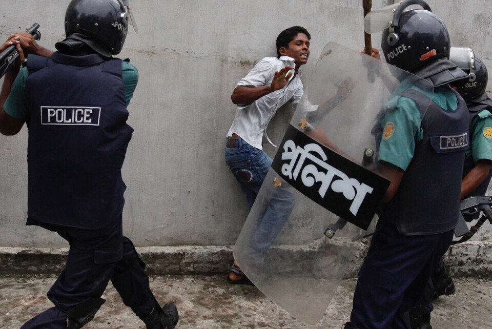 Politiet angriper en demonstrerende tekstilarbeider i Bangladesh´hovedstad Dhaka. Foto: Andrew Biraj / NTB scanpix