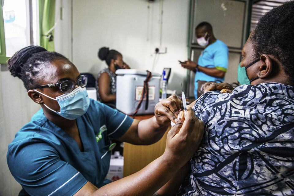 Joesephine Namayanja (med ryggen til) vaksineres av sykepleier Caroline Ikiring under en vaksineringskampanje av helsearbeidere i Uganda. Landet har så langt satt 300 000 vaksinedoser mot covid-19, men ligger i likhet med mange andre afrikanske land milevis bak Nord-Amerika og Europa i vaksinedekning. Gapet i tilgang på vaksiner mellom rike og fattige land vil vare ved ut hele 2021. Foto: Sofi Lundin.
