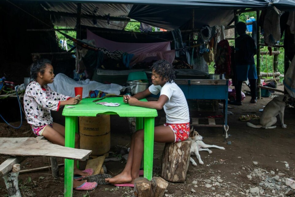 Døtrene til noen av arbeiderne spiller kort på et bord i den midlertidige leiren arbeiderne har fått satt opp. Forholdene de lever under er ytterst primitive.