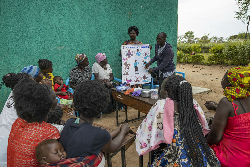 I skyggen av et tre sitter kvinner og lytter når representanter fra Redd Barnas lokale partner, WoMena underviser om menstruell helse.