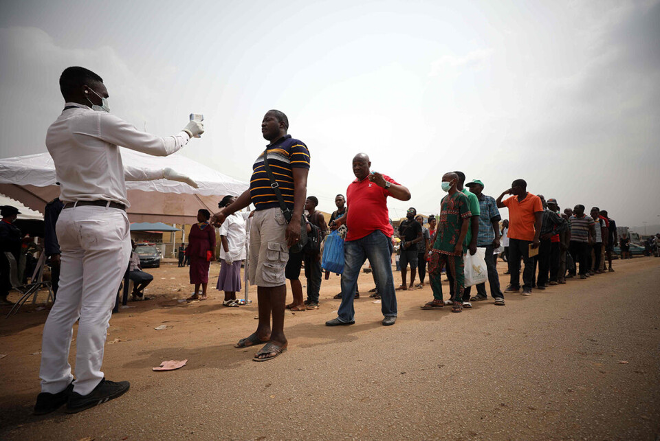 En helsearbeider måler temperaturen til folk som ønsker å passere grensen mellom hovedstaden Abuja og delstaten Nasarawa etter at president Muhammadu Buhari erklærte «lock-down» i Nigeria for å hindre koronasmitte. Foto: Kola Sulaimon / AFP / NTB scanpix