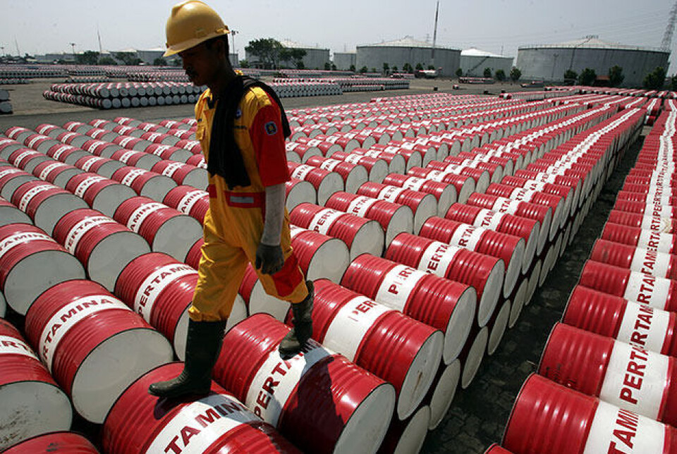 En ansatt i Indonesias statsoljeselskap Pertamina skritter over oljefat på et lager i Djakarta. Subsidier på olje og annen fossil energi har slukt stadig større summer på landets statsbudsjett. Nå gjør det internasjonale oljeprisfallet det enklere å fase ut subsidiene. Foto: Beawiharta/REUTERS/NTB Scanpix
