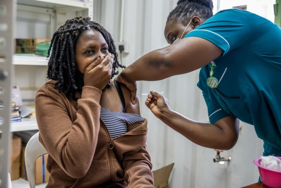 Priscillah Invester (22), jordmor ved et sykehus i Ugandas hovedstad Kampala, får sin første dose vaksine mot covid-19. Foto: Sofi Lundin
