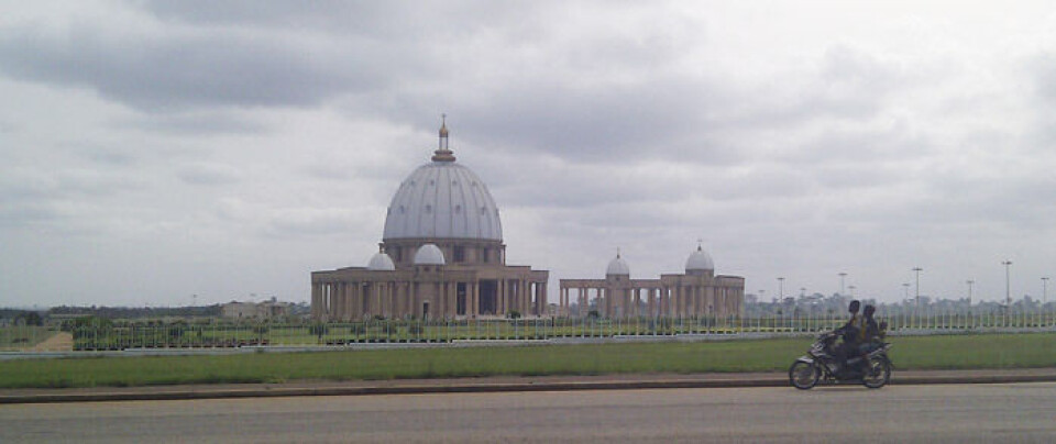 Verdens største kirke i Yamoussoukro, Elfenbenskysten. Den står der som en... visjon. Med sine gresk-romerske kolonner, bronseklokker, enorme kuppel, og forgylte lanterne, stiger den opp av Yamoussoukros irrgrønne horisont og bølgeblikktak, skriver Gylver Foto: Privat
