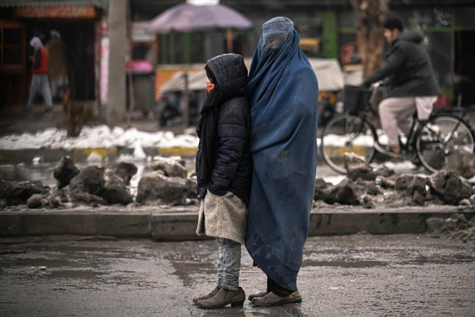 En burka-kledd kvinne og hennes barn står midt i trafikken i Kabul og tigger 8. januar i år. Tiggere er et vanlig syn i dagens Afghanistan. Foto: Mohd Rasfan / AFP / NTB