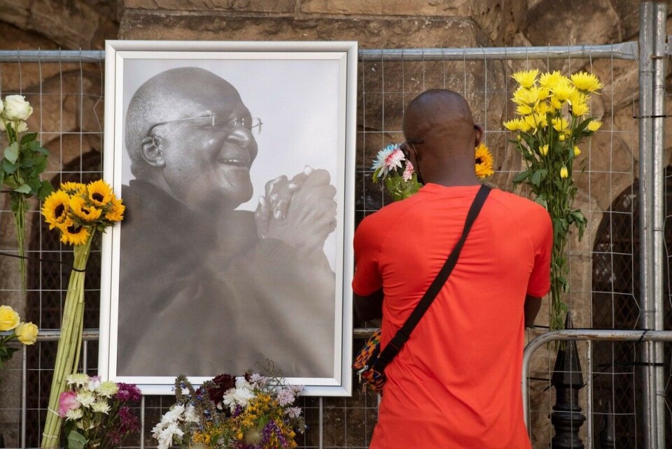 En sørgende bringer blomster til minnested for erkebiskop Desmond Tutu foran St. Georges-katedralen i Cape Town. Foto: Rodger Bosch / AFP / NTB