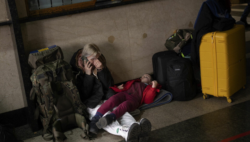 En mor og datter venter på togstasjonen i Kiev i dag. Russlands invasjon av Ukraina har allerede resultert i at over 100 000 er på flukt, ifølge Redd Barna.