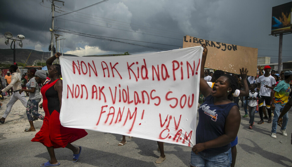 Mennesker i Port-Au-Prince protesterer med et banner som lyder: «Nei til kidnappinger, nei til vold mot kvinner».