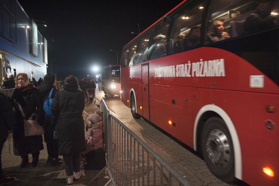 Busser med flyktinger strømmer til mottakssenteret utenfor grensebyen Korczowa i Polen. Av de mange som kommer venter på å reise videre inn i Polen er seks år gamle Nika (i rosa) og hennes mor Svitlana (helt til venstre). Neste stopp Warsawa.