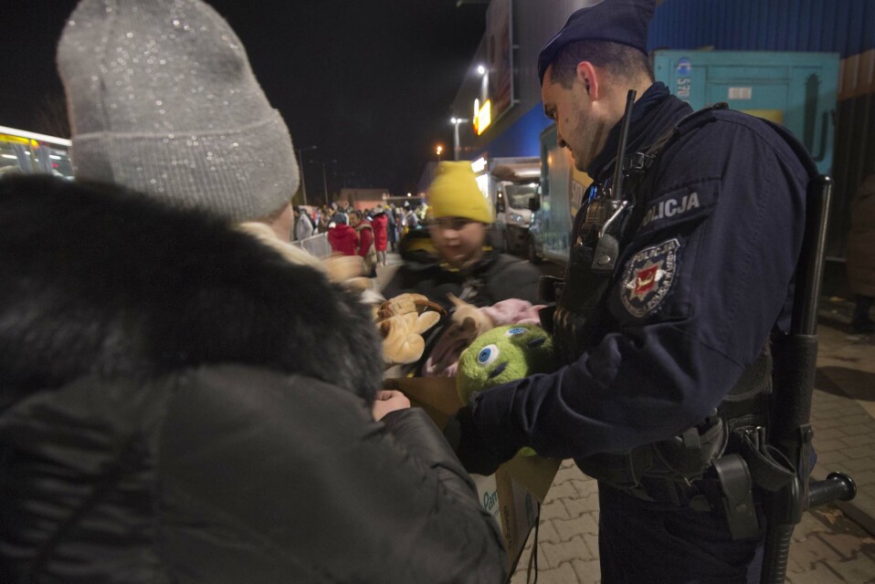 En politimann deler ut kosedyr til barna på mottakssenteret i Korczowa.
