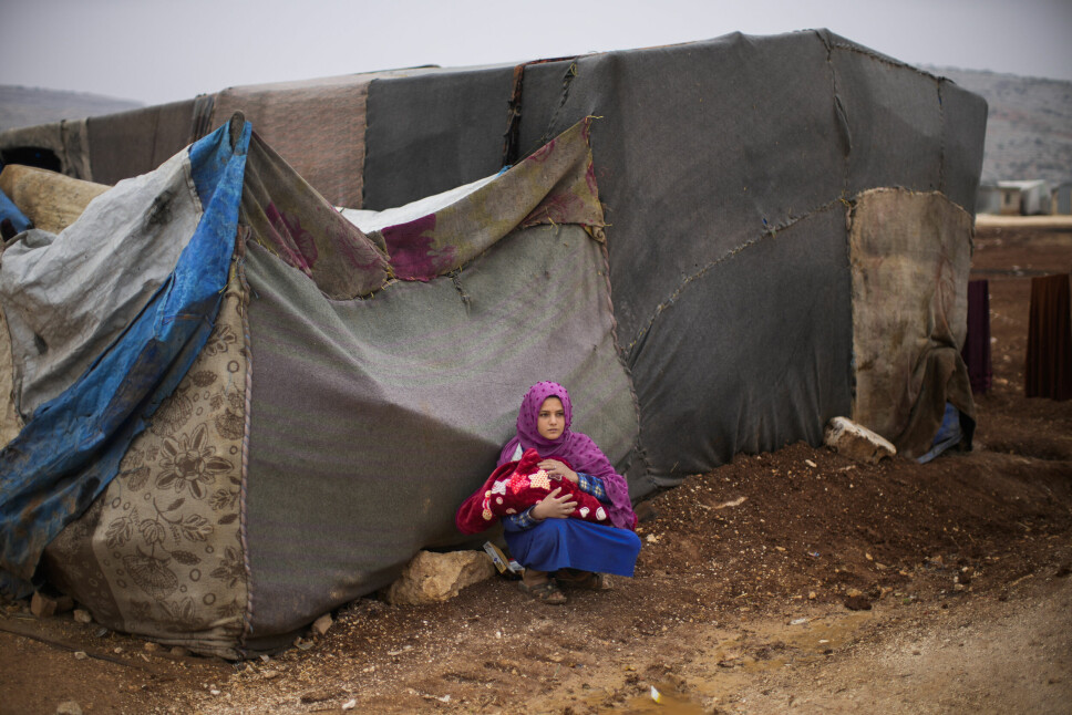 Stadig flere syrere er avhengige av bistand for å overleve, og krisen er ytterligere forverret som følge av krigen i Ukraina. Her holder en ung kvinne en baby i armene i en flyktningleir for internt fordrevne syrere i Sarmada-distriktet nord for Idlib i Syria.
