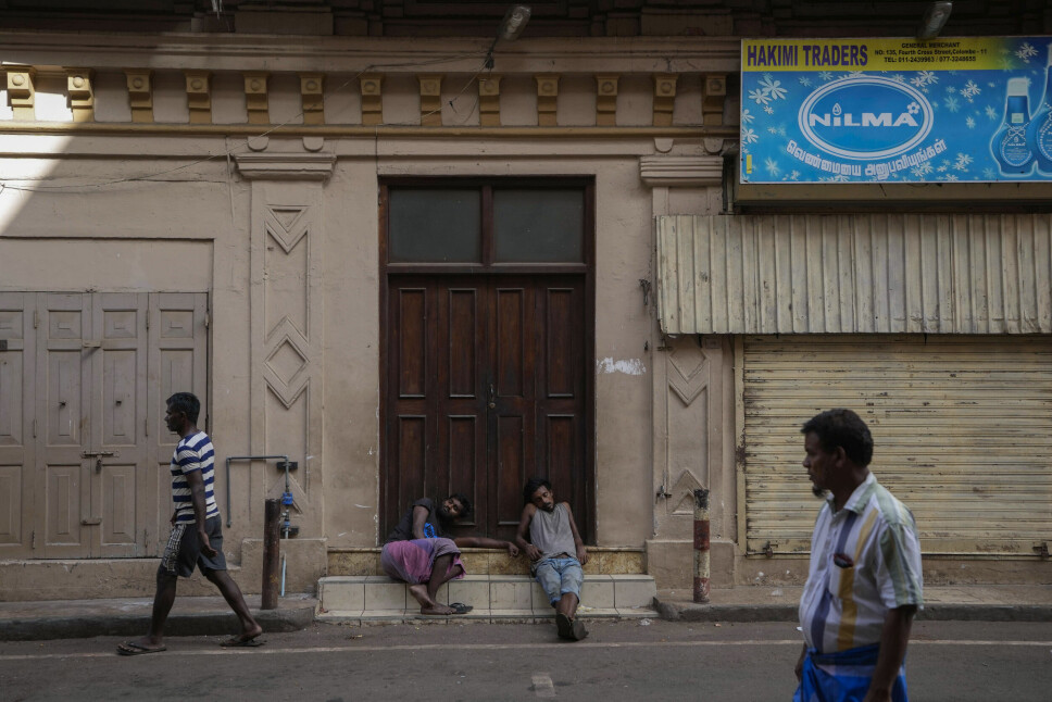 Økonomisk vanskelige tider på Sri Lanka har ført til nedstengninger i de store byene. For skolebarn betyr det blant annet bortfall av ett av dagens måltider. Bildet viser arbeidere som venter på at en dagligvarebutikk skal åpne i Colombo på Sri Lanka 26. juni.