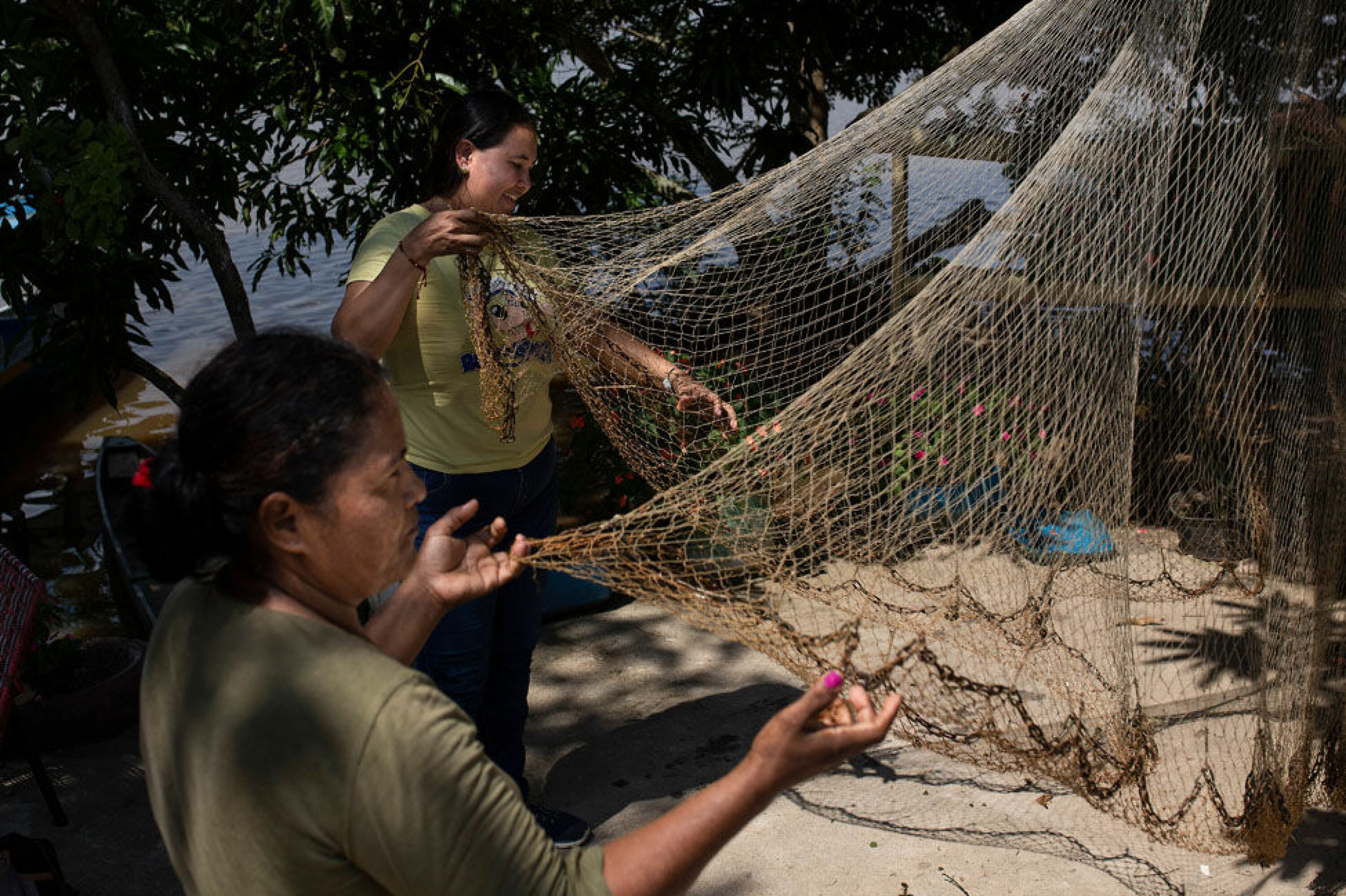 Liudmila Alemus (t.v.) og Yuly Velazquez gjør klar garnene de bruker til å fiske i sumpen ved Magdalena-elven nord i Colombia.