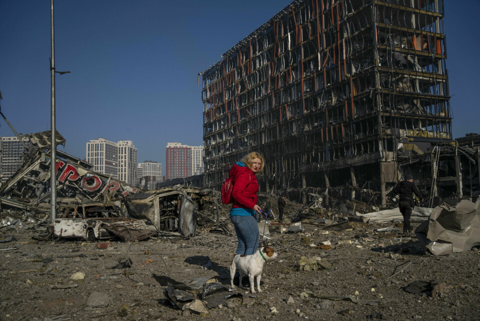 En kvinne går tur med hunden sin i ruinene fra et utbombet kjøpesenter i Kyiv 21. mars. Foto: Rodrigo Abd / AP / NTB