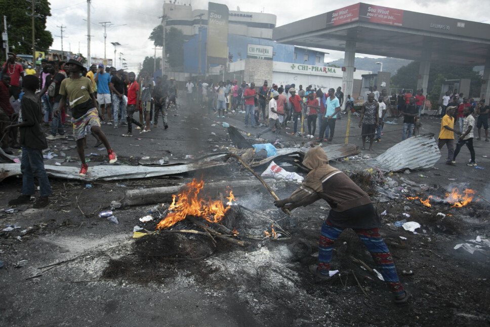 Demonstranter samler seg rundt en barrikade som er satt opp i protest mot økte drivstoffpriser, mandag 19. september. FNs Haiti-utsending sier at det utspiller seg en humanitær katastrofe i landet etter to uker med voldelige opptøyer