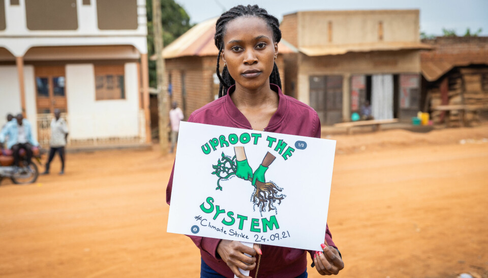 Patience Nabukalu (26) holder opp et skilt etter en protest under Global Climate Stike. Hun og en rekke aktivister dro fra Kampala ut på landsbygden i Uganda for å demonstrere.
