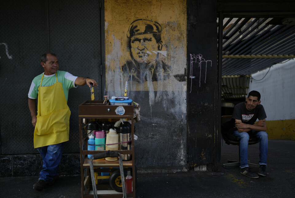 Et veggmaleri av tidligere president Hugo Chávez pryder veggen der en kaffeselger venter på kunder i Caracas, tirsdag 28. februar. Omtrent tre fjerdedeler av venezuelanerne lever for mindre enn 1,90 dollar om dagen. Minstelønnen som betales i bolivar, tilsvarer rundt 50 kroner per måned. Foto: Ariana Cubillos / AP / NTB
