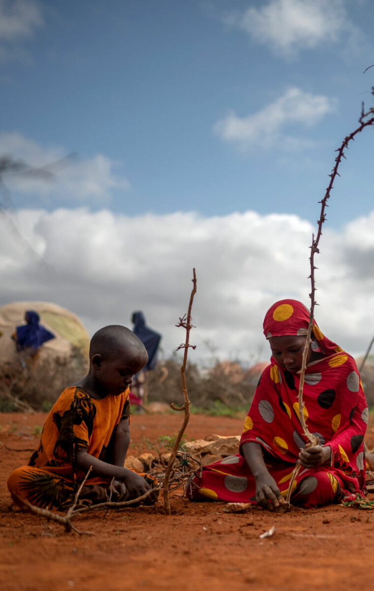 A girl and her niece build a tent from sticks and rags on the edge of Baidoa, in southern Somalia, on Nov. 3, 2022. Over 165,000 refugees have streamed into Baidoa since early last year, fleeing the ravages of SomaliaÕs fiercest drought in 40 years. (Andrea Bruce/The New York Times)