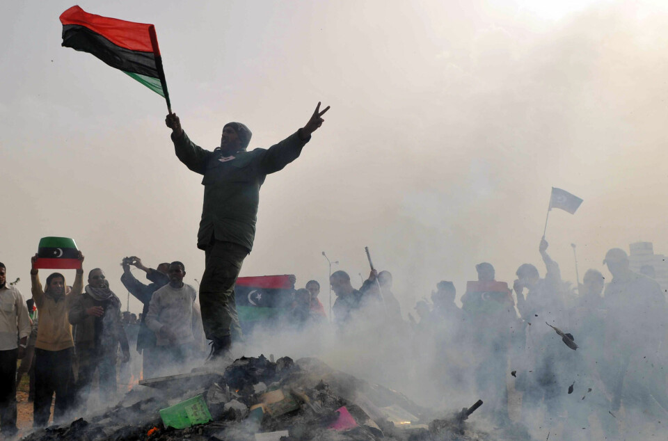 Benghazi, 2. mars 2011: En libyer viser seierstegn mens han står på toppen av en haug med brente bøker, forfattet av Libyas leder Moammar Gadhafi.