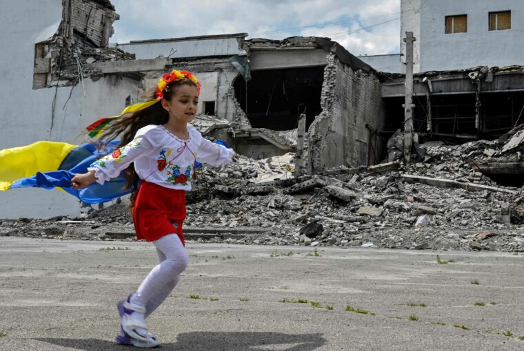 Et barn løper med et ukrainsk flagg foran det krigsødelagte kultursenteret i byen Derhachi, i Kharkiv, 17. juni 2023.