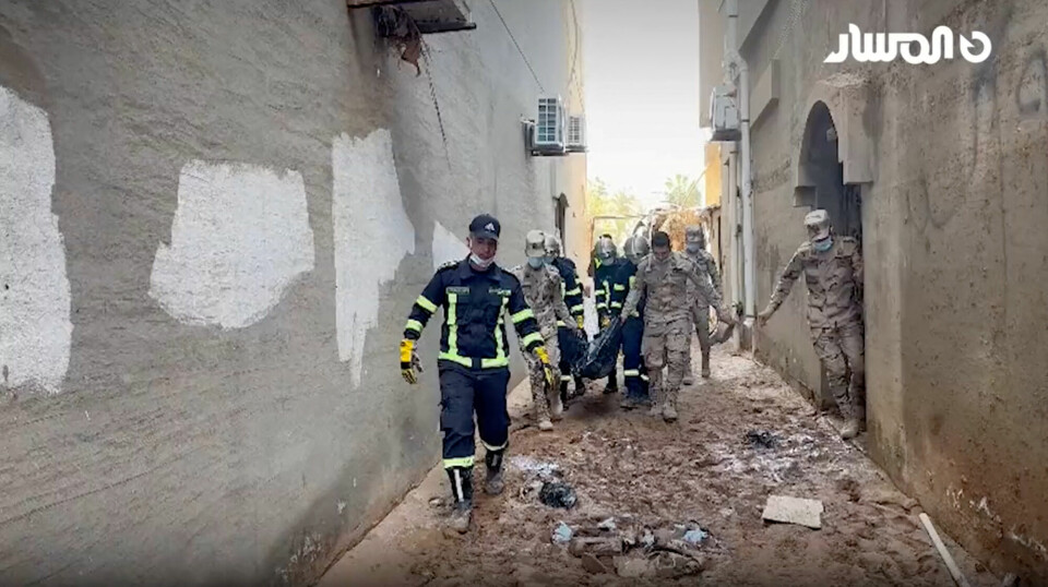 Libyske redningsarbeidere bærer ut et lik fra ødelagte hus i byen Derna onsdag. Foto: AL-Masar TV / Reuters / NTB