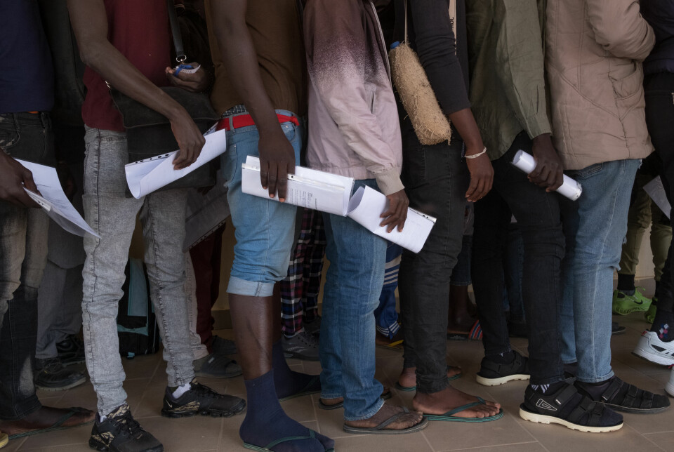 Migranter fra Mali venter ved Agadez flyplass. I hendene holder de nye id-dokumenter.