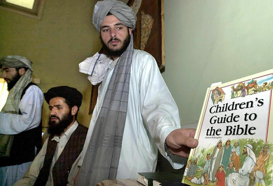 IAM ble også anklaget for misjonering da Taliban hadde makten forrige gang. Bildet er fra 2001 og viser en Taliban-embetsmann som holder fram en bok de angivelig fant på IAM sitt kontor. Den sveitsiske organisasjonen aviste anklagene den gang og gjør det nå også.