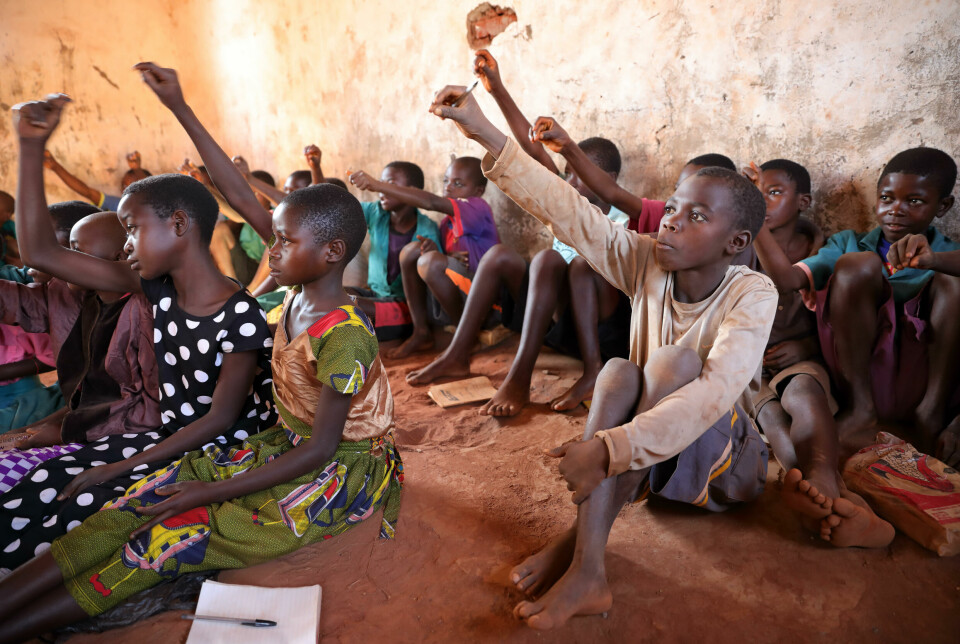 Elever rekker opp hånden i et klasserom i landsbyen Ntchisi i Malawi.