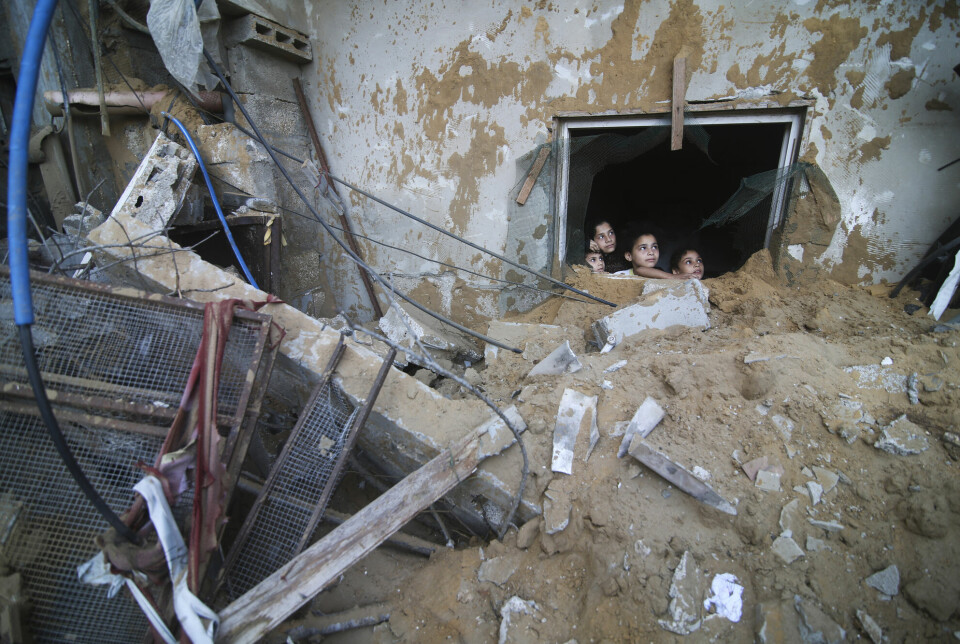 Palestinske barn ser ut av huset de bor i og over på nabobygningen som ble ødelagt i israelske luftangrep mot byen Rafah i Gaza lørdag 14. oktober.