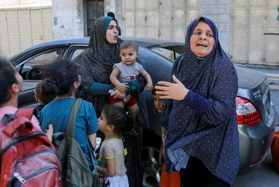 Palestinske mødre og barn venter på transport etter bombeangrep i Gaza City søndag 15. oktober. Israel har bedt en million palestinere evakuere til den sørlige delen av Gaza-stripen.
