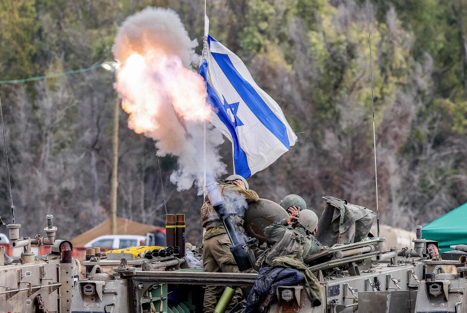 Israelske soldater holder seg for ørene i det de fyrer av ammunisjon fra et pansret kjøretøy ved grensen sør i landet. Bildet er tatt 3. januar i år.