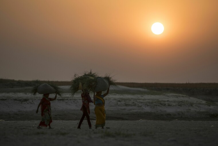 Bønder går langs elven Ghaghara i Revelganjghat, India.