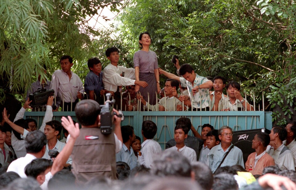 University Avenue, Yangon, 1995: Aung San Suu Kyi taler til følgere i porten til den etterhvert ikoniske eiendommen ved Inya Lake, etter fem år i husarrest. Nå har Myanmars høyesterett bestemt at huset skal selges etter en årelang familiefeide om eiendommen.