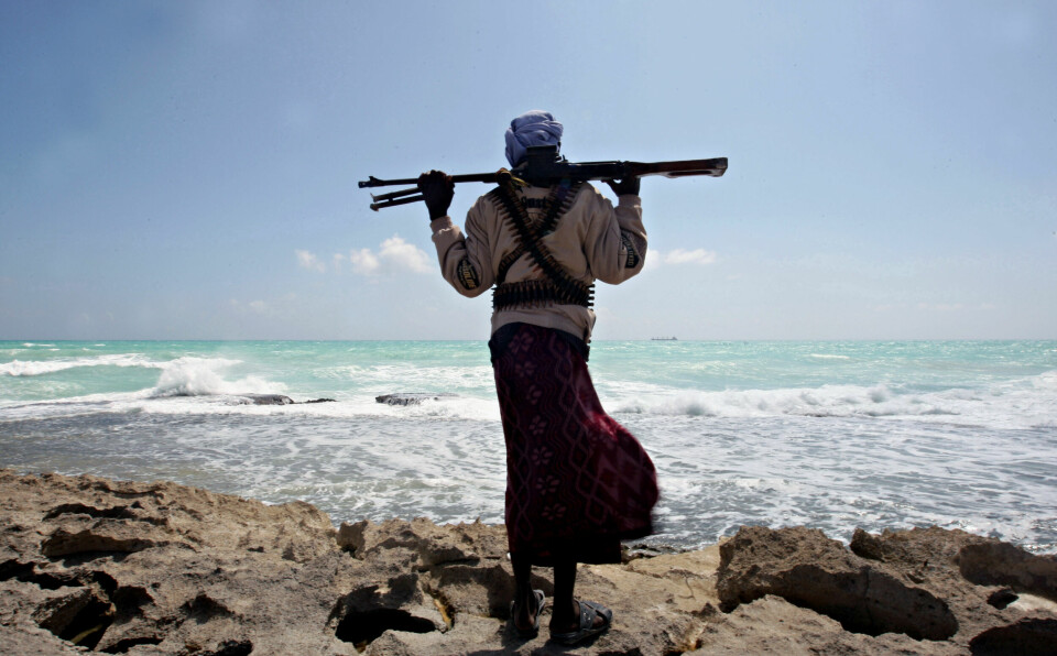 Photo made on January 7, 2010 shows an armed Somali pirate along the coastline while the Greek cargo ship, MV Filitsa, is seen anchored just off the shores of Hobyo town in northeastern Somalia where its being held by pirates. A six-nation east African regional bloc on February 1, 2010 urged Somalia's two breakaway regions of Puntland and Somaliland to jointly battle Islamist militia which it said had extended to the areas.  AFP PHOTO/ MOHAMED DAHIR