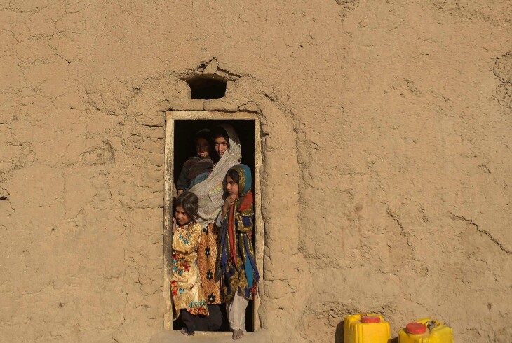 En afghansk familie står ved døren til hjemmet sitt i landsbyen Haji Rashid Khan i Bala Murghab under en tørkeperiode i 2021.