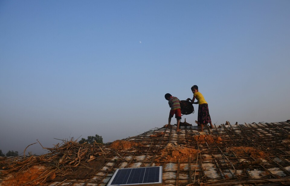 To unge rohingya-flyktninger legger ut ved til tørk på taket av en hytte i flyktningleiren Cox's Bazar i Bangladesh.