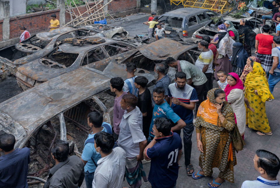 Folk ser på utbrente biler etter sammenstøtene mellom demonstranter og politiet i Dhaka, Bangladesh, i sommer.