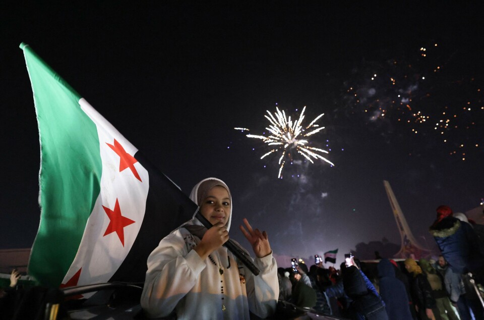 En ung kvinne holder opp det syriske flagget under det som er den første nyttårsfeiringen etter Assads-regimets fall.