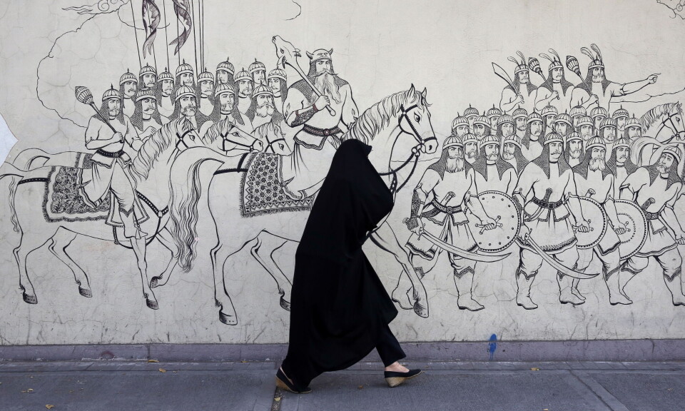 FN mener myndighetene har gått fra ekstrem voldsutøvelse da protestene pågikk for fullt i 2022 til en stille, pågående undertrykkelse. Bildet viser en iransk kvinne som går forbi et veggmaleri av menn som kriger i hovedstaden Teheran.