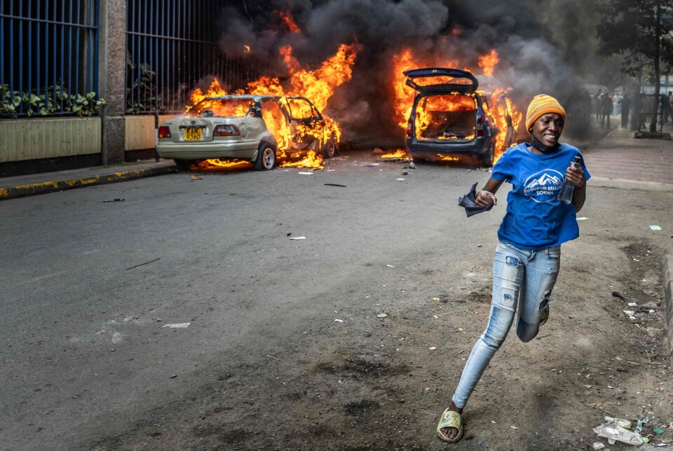 En forbipasserende løper i panikk forbi brennende biler under sammenstøt mellom demonstranter og politi i hovedstaden Nairobi 12. juni. Protestene ble utløst av dødsfallet til den kenyanske bloggeren Albert Ojwang i politiets varetekt, samtidig som regjeringen la frem budsjettet for 2025–2026. Politiet har slått hardt ned på demonstrasjonene.