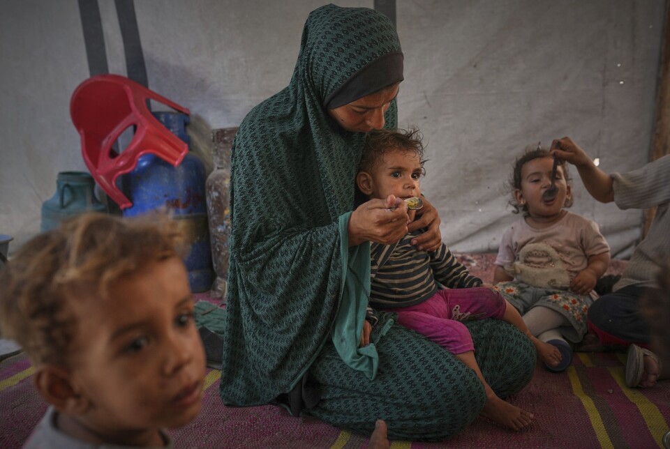 En palestinsk kvinne mater barna sine i et telt som huser internt fordrevne i Gaza, i mai i år.