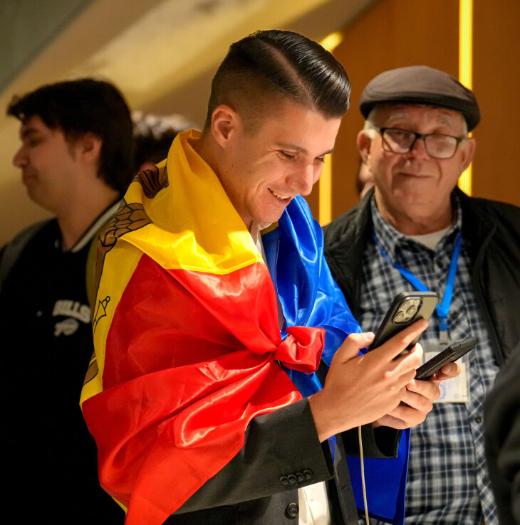 En støttespiller for regjeringspartiet PAS ikledd det moldovske flagget smiler fornøyd i det han sjekker de første valgresultatene på mobiltelefonen sin søndag kveld.